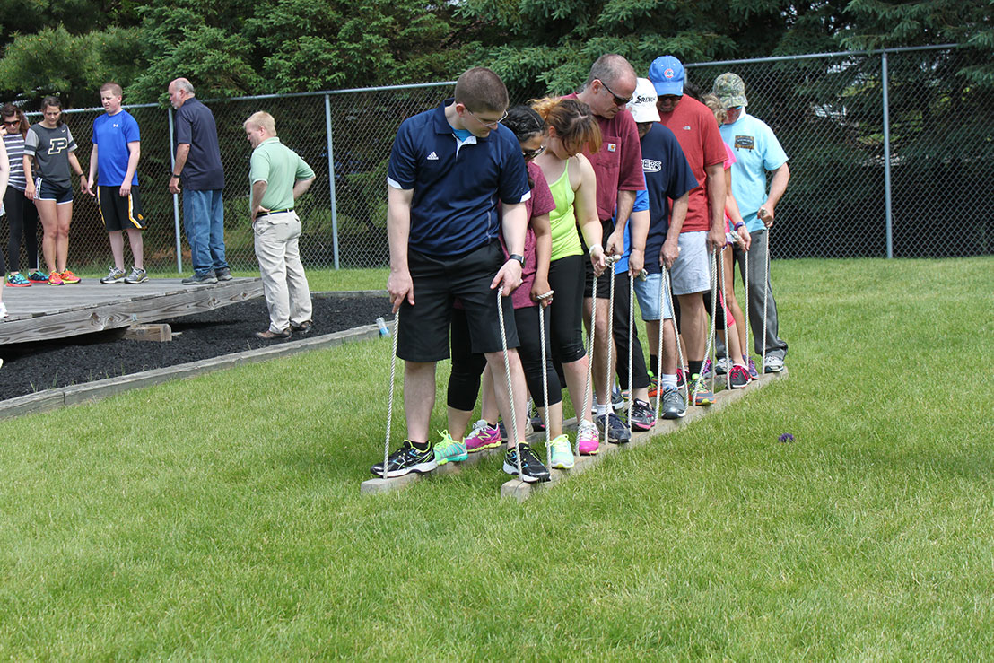 A group of adults participate in a team building exercise.