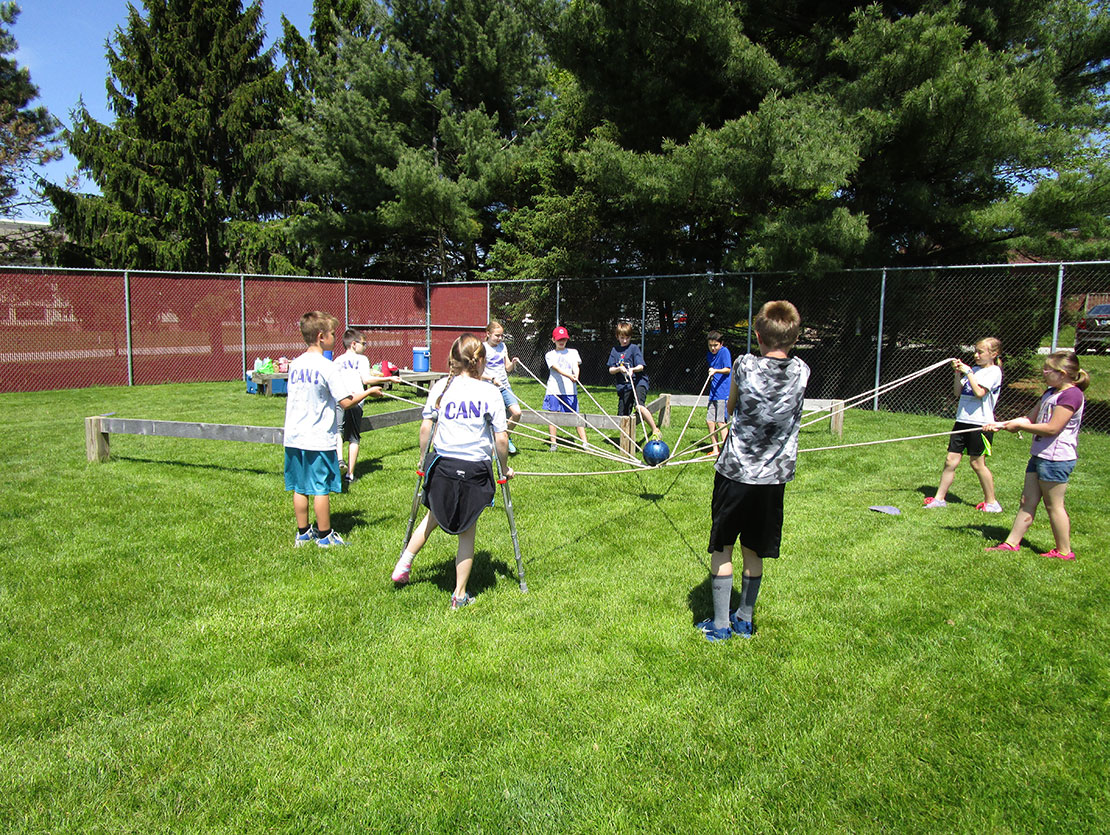 an elementary school class works together on a Beyond Boundaries Challenge Course obstacle.