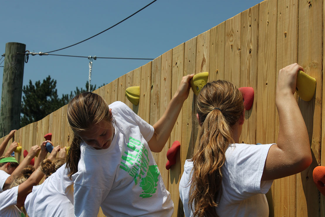 An athletic team navigates the climbing wall challenge.